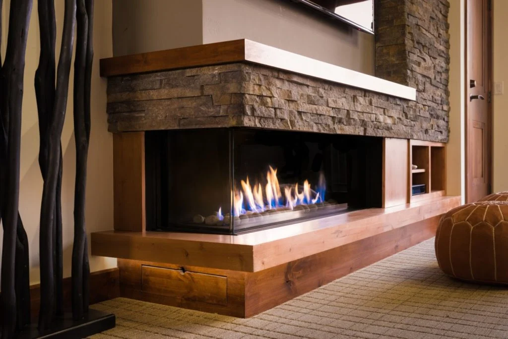 Cozy fireplace with stone wall and wood flooring, featuring a mantel for added charm and functionality