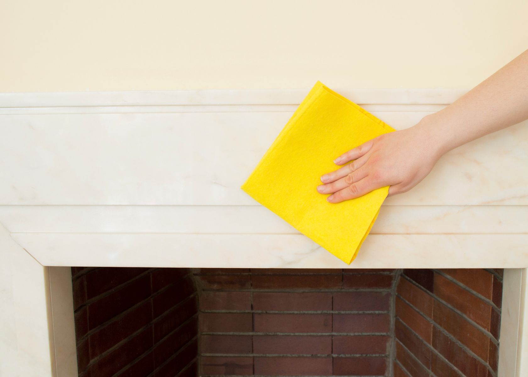 A person cleaning a fireplace with a yellow cloth