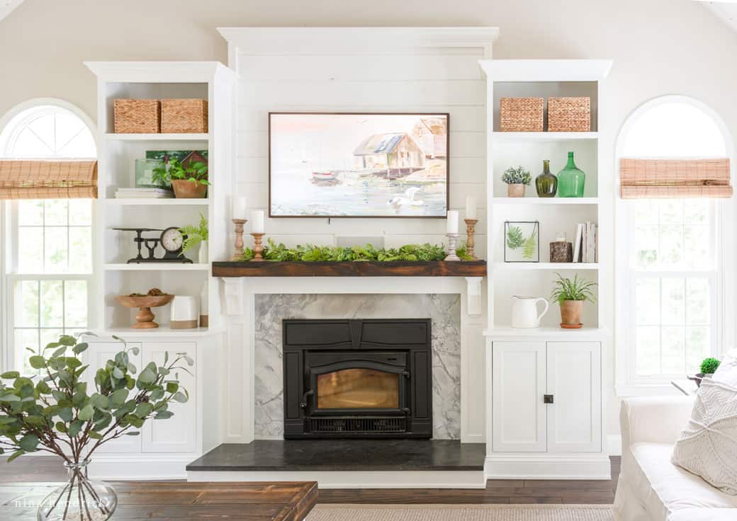 A white fireplace with a picture on the wall