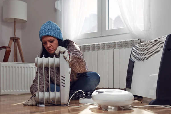 A woman repairs an electric heater in front of a radiator. Learn how to maintain an electric heater