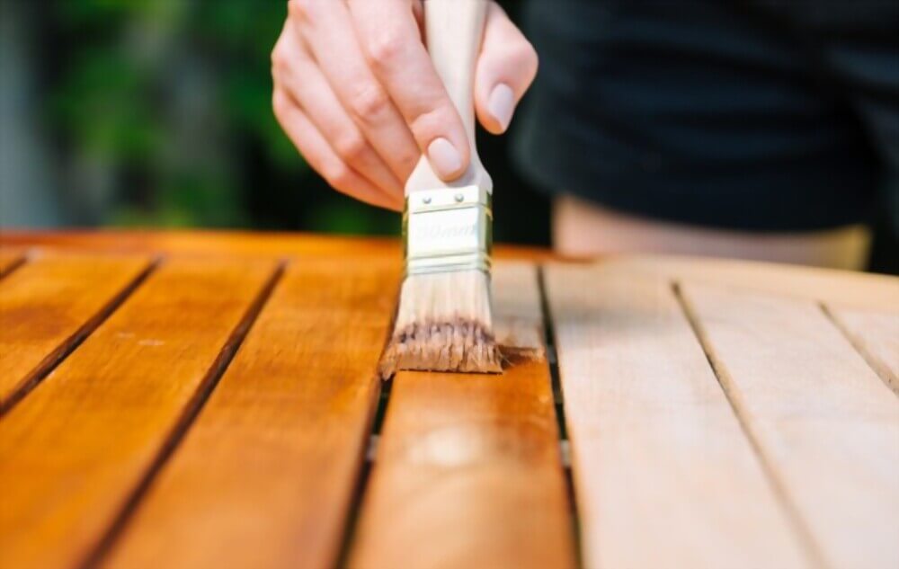 A person painting a wooden table with a brush
