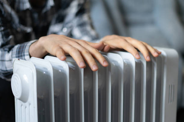 A man holding a heating radiator, ensuring safety and efficiency of oil-filled heaters