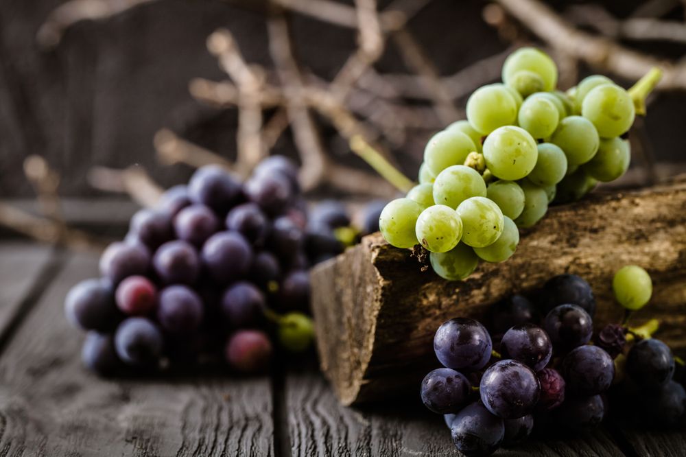  Fresh grapes arranged neatly on a wooden table, with inadequate shade for their preservation