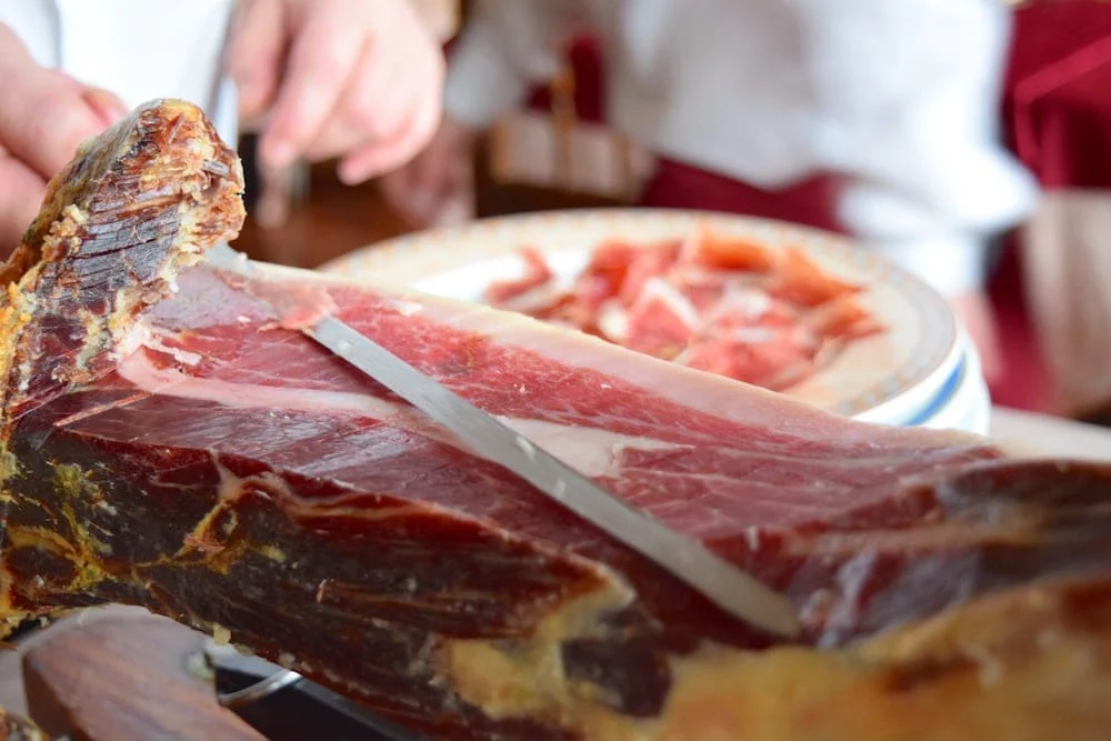 Expertly cutting Spanish Iberian Ham on a table