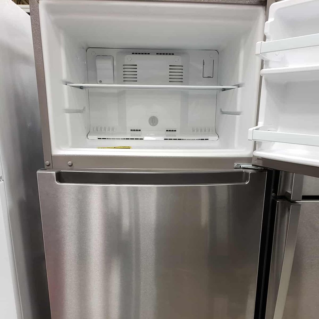 A silver refrigerator with an open door, revealing its empty freezer compartment