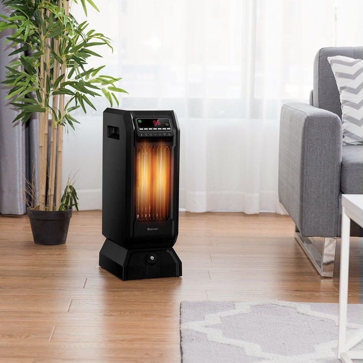 A black electric heater on a wooden floor.