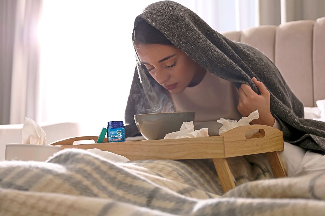 A woman in a blanket sits on a bed