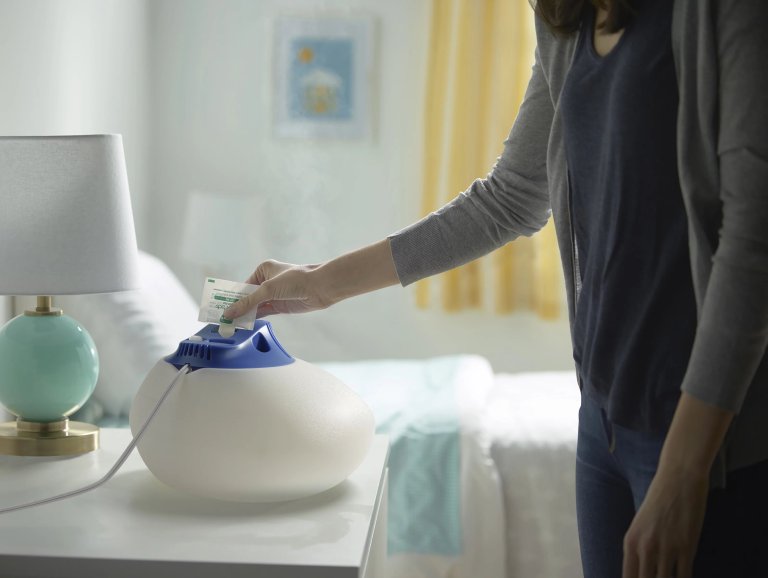 a woman inserting a water bottle into a humidifier