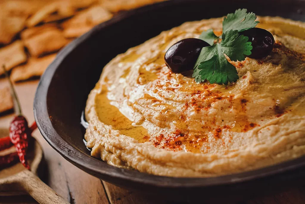 Hummus with olives and pita chips, a delicious snack with Mediterranean flavors. Perfect for all palates