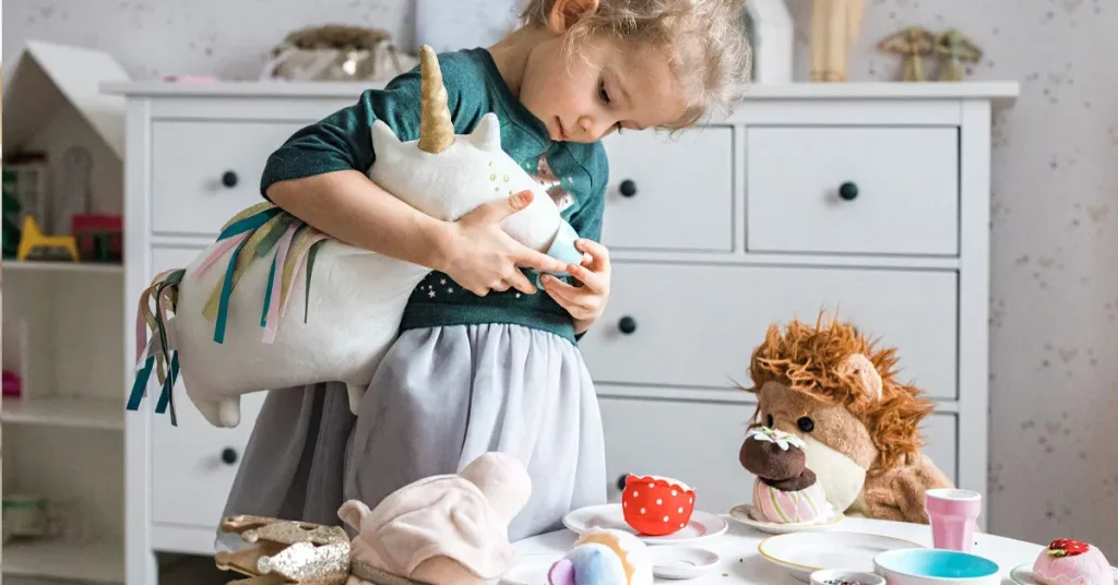 A young girl joyfully engages with her stuffed animals, showcasing the emergence of symbolic play